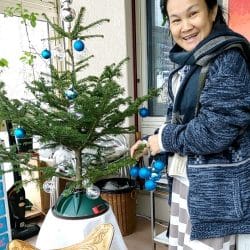 Thaifrau schmückt Weihnachtsbaum in der Schweiz